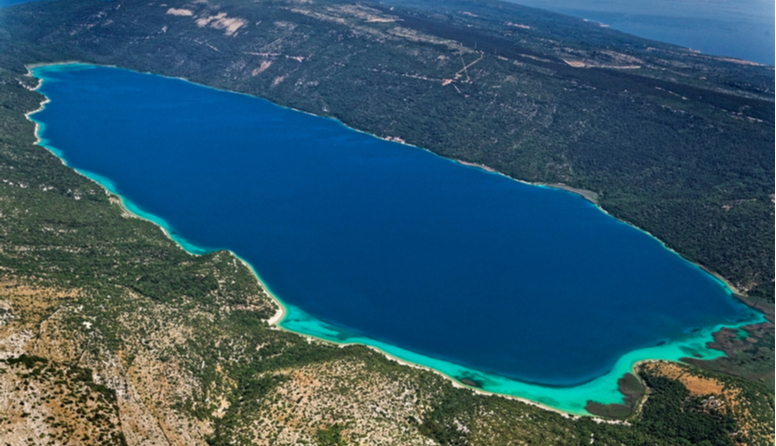 Fotografija prikazuje udubljenje na kopnu ispunjeno vodom. Vransko jezero na otoku Cresu.