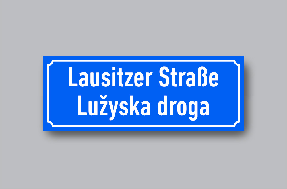 Slika prikazuje cestovnu oznaku mjesta na njemačkome i jeziku Lužičkih Srba Lausitzer Straße / Lužyska droga.