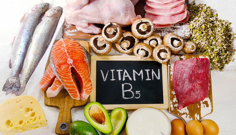 Fotografija prikazuje crveno mseo, ribu, file lososa, piletinu, sjemenke, avokado, jaja sir. Na crnoj pločici je napisano VITAMIN B 5.