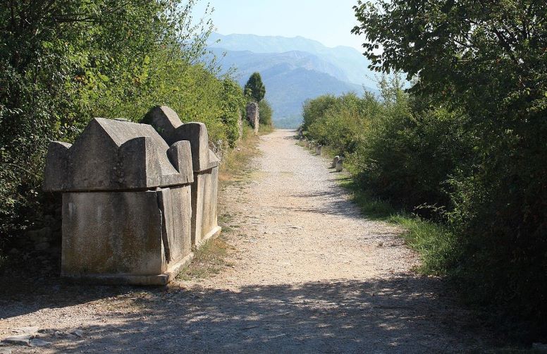 Uz makadamsku cestu vidi se kameni sarkofag, U donjem dijelu je poput kvadra, a u gornjem dijelu je stožasi poklopac obrađenih rubova.