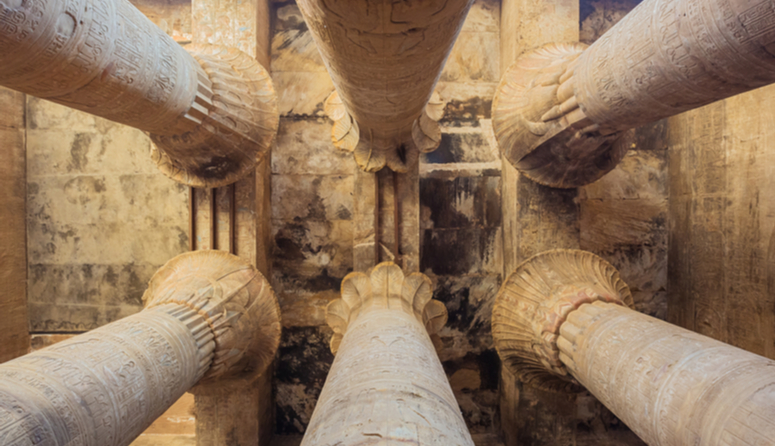 Unutrašnjost Horusova hrama u Edfu. Strop podupiru monumentalni, sivi, stupovi s ukrasnim zlatnim dijelom u podnožju. 