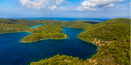 Jezero usred kojeg je otok. U daljini se vidi more, a otok je zelen