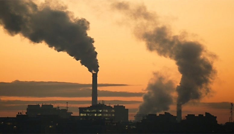 Fotografija prikazuje dimnjake industrijskog postrojenja iz kojih izlazi gusti, tamnosivi dim.