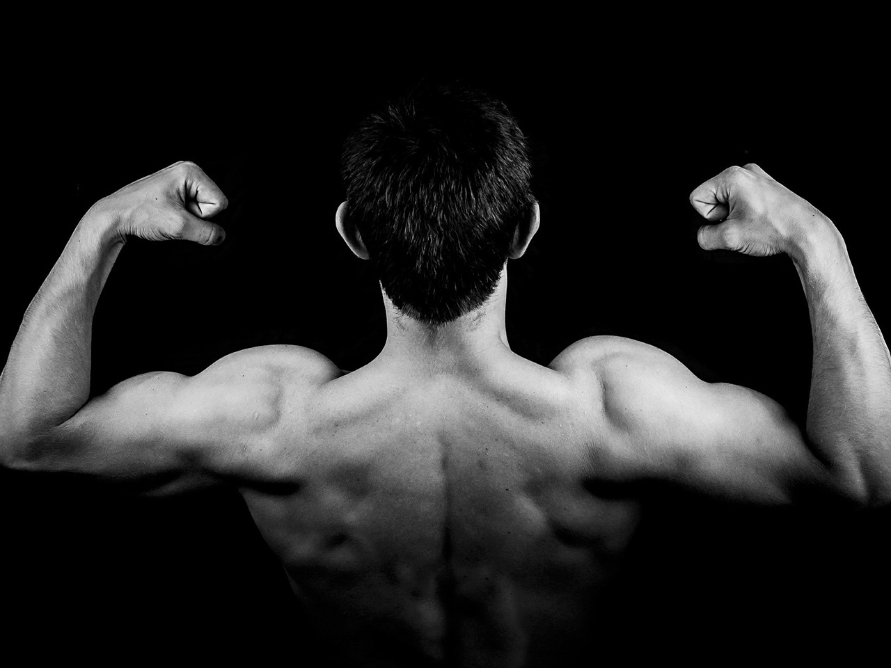 Snimljen s leđa, muškarac golog torza napinje bicepse obje ruke.