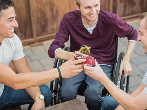 A guy in a wheelchair and two guys without any disabilities hanging out