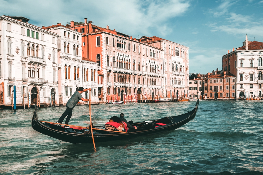 Na fotografiji su u prvom planu more i gondola, a u drugom planu građevine.