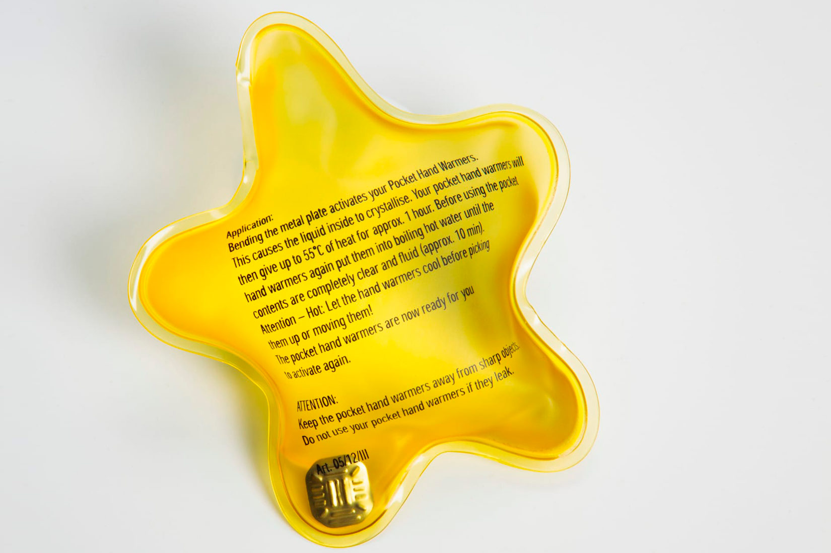 Fotografija prikazuje plastični, žuti grijač za ruke zvjezdastog oblika.