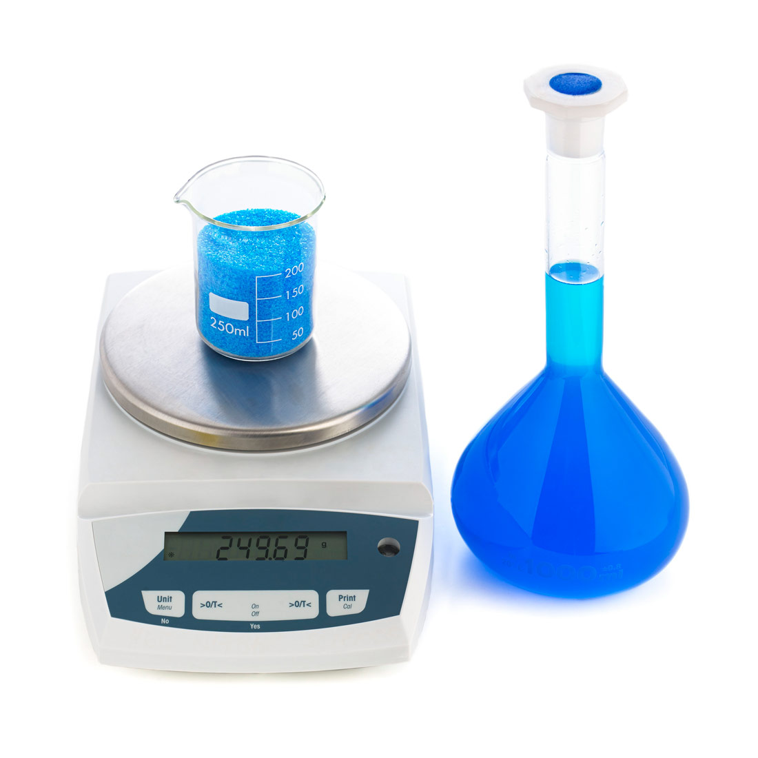 Fotografija prikazuje laboratorijsku vagu na kojoj se nalazi menzura s vodenom otopinom bakrova(II) sulfata. Pored laboratorijske vage nalazi se odmjerna tikvica u kojoj se nalazi otopina modre galice.