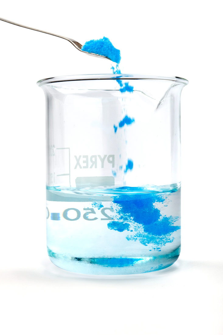 Na slici je prikazana laboratorijska čaša s vodom u koju sa žličice pada plavi prah modre galice.U staklenu čašu koja je graduirana (crtice koje označavaju volumen ) nalazi se voda do oznake 250 mL. Odozgo iz žlice sipa se prah modre galice koja je plave boje. Prikazano je kako se prah oatapa u vodi i boji vodu u plavo.