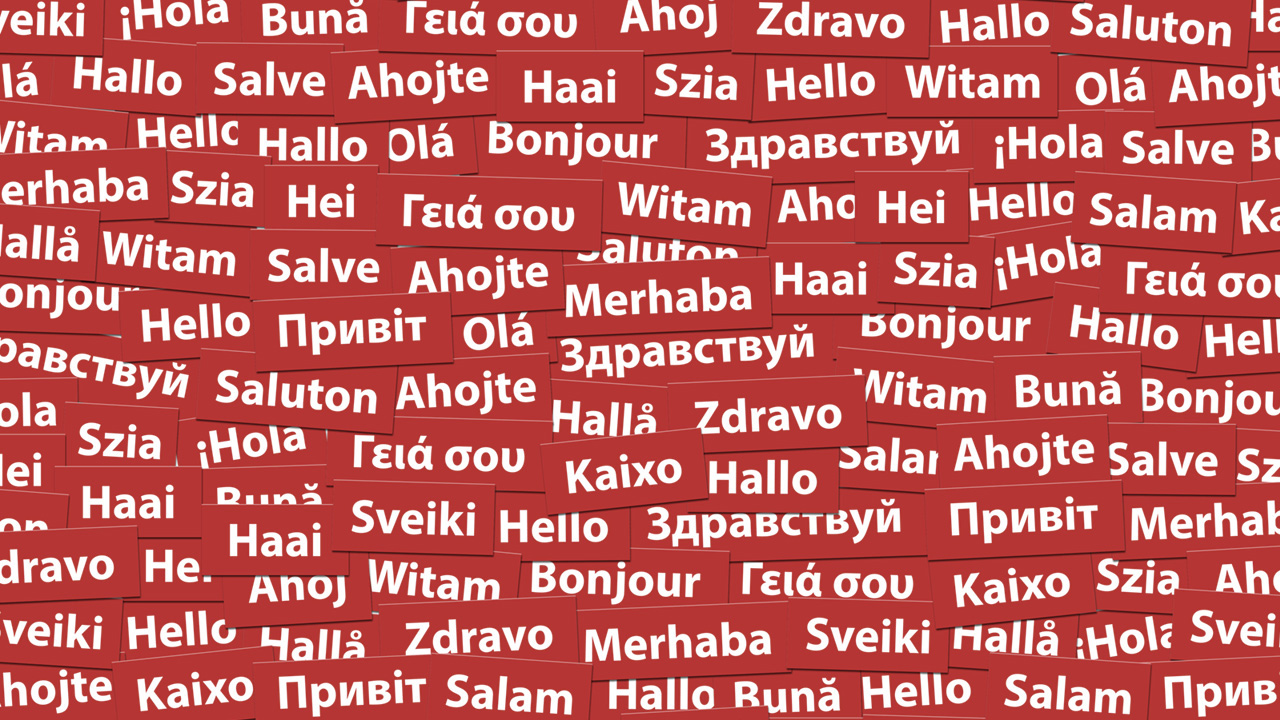 Bijelim slovima na crvenoj podlozi napisani su pozdravi na različitim svjetskim jezicima. 