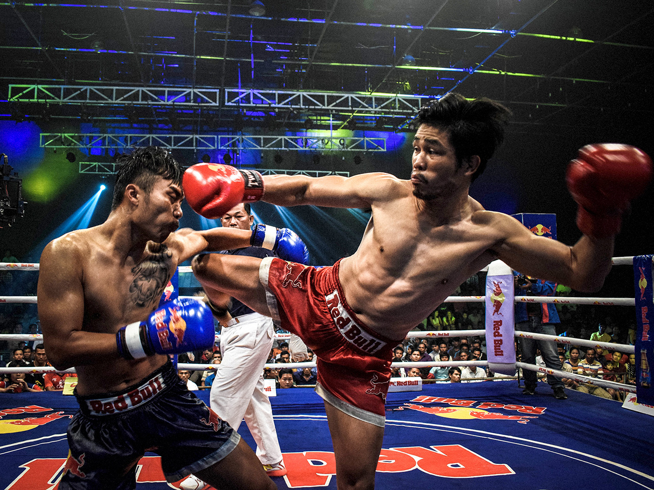 Borba dva borca tajlandskog boksa pred sucem i prepunim gledalištem.