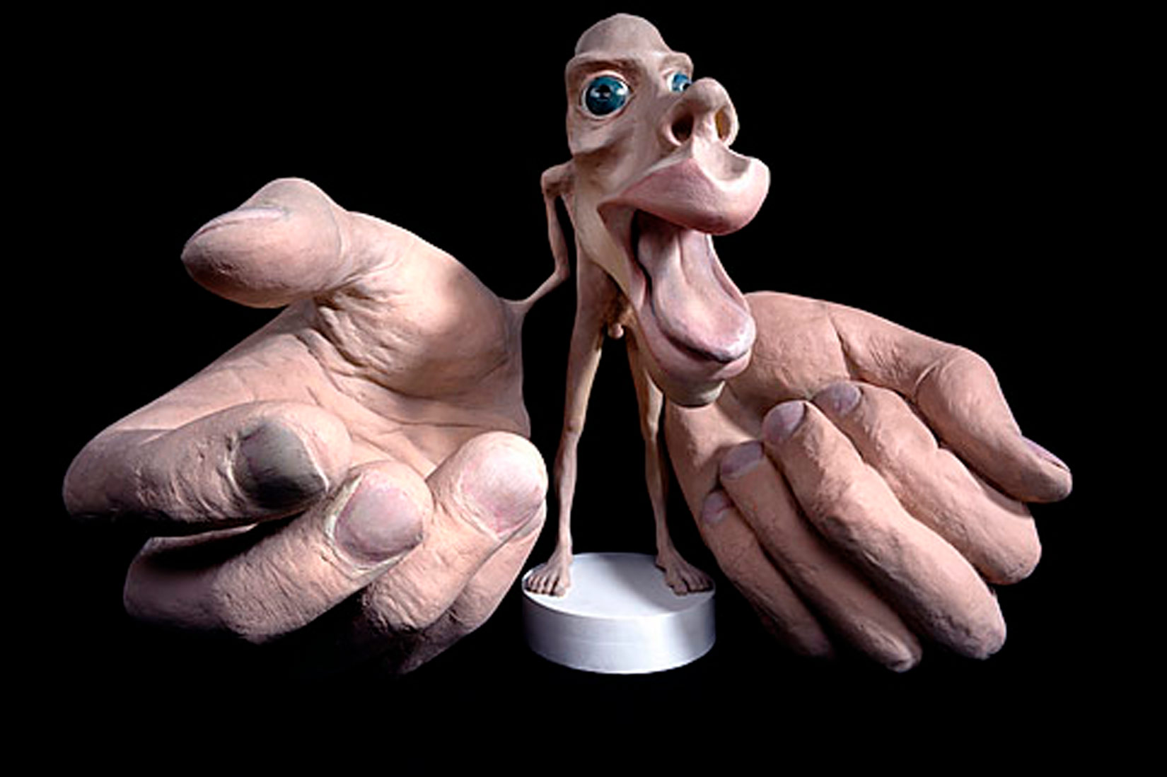 Prikazan je model uvećanih dijelova tijela na gipsanoj skulpturi. Velikim su prikazane oči, nos i usta, te vrlo velike pake ruku s ogromnim prstima. Unutar velikih usta nalazi se veliki jezik.