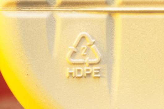 Fotografija prikazuje oznaku za recikliranje utisnutu na dnu boce. Oznaka se sastoji od 3 strelice savinute u oblik trokuta. U sredini trokuta je otisnut broj 2, a ispod trokuta slova HDPE. Ova oznaka govori da se radi o polietilenu visoke gustoće.