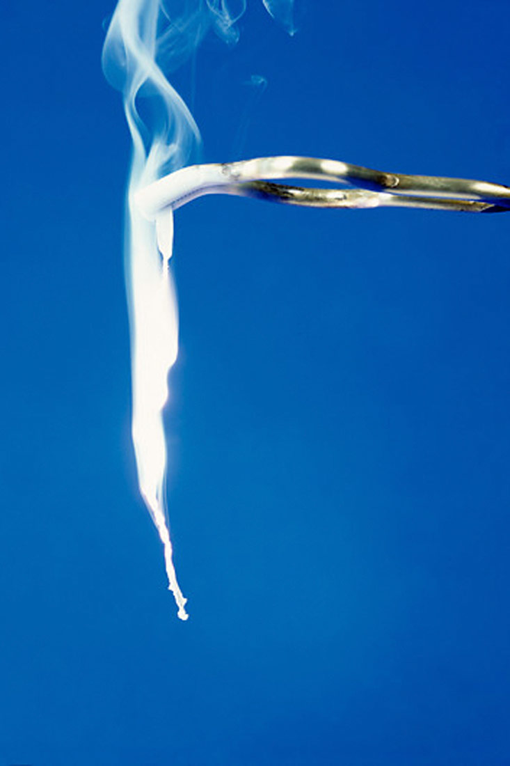 Na slici s plaavom podlogm je prikazano gorenje magnezijeve vrpce koja izgleda kao svijetla nit iz koje ide dim.Vrpca se drži između metalnih hvataljki poput kliješta .