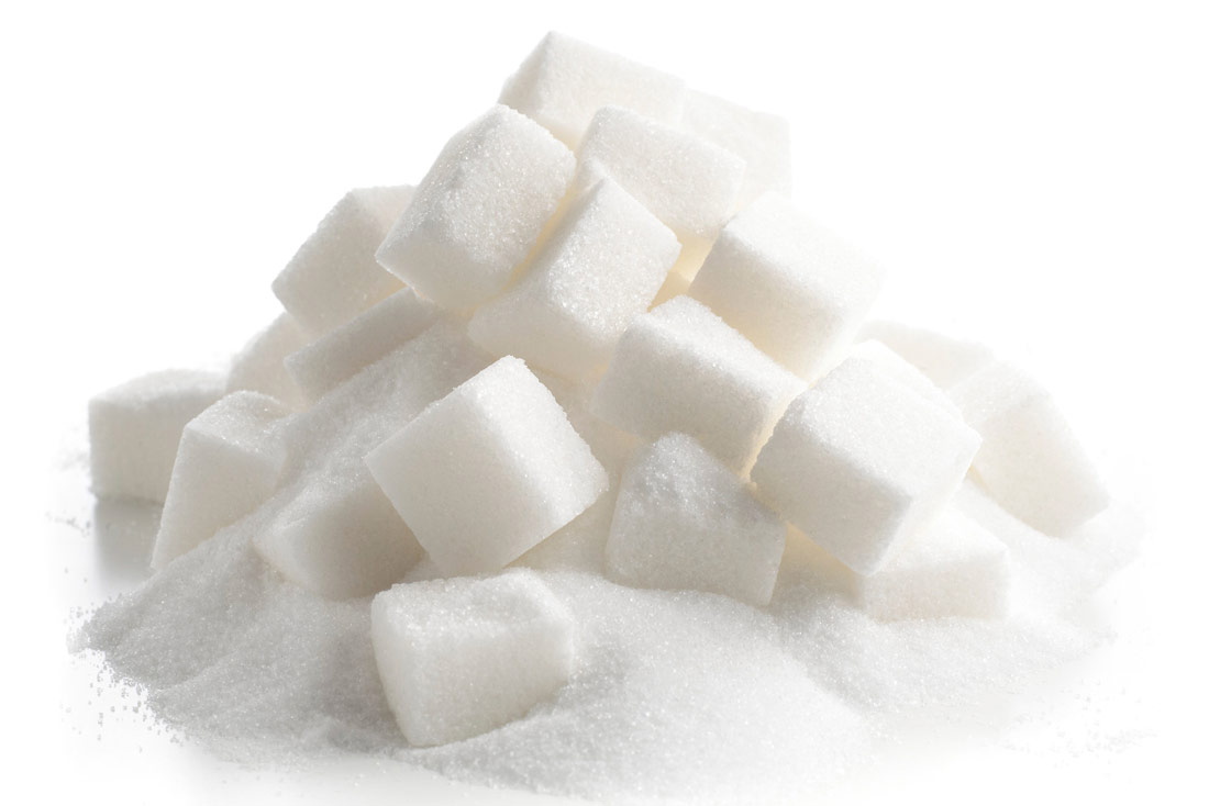 Prikazana je hrpica bijelog šećera. Na dnu su rasuti kristalići šećera, a na njima su kocke bijelog šećera.