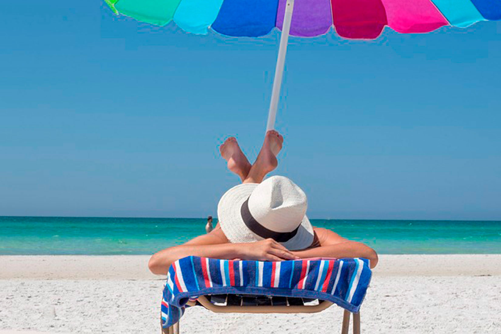 Slika 3. Prikazana je žena na plaži na ležaljci. ima na glavi šešir, a iznad nje je suncobran.