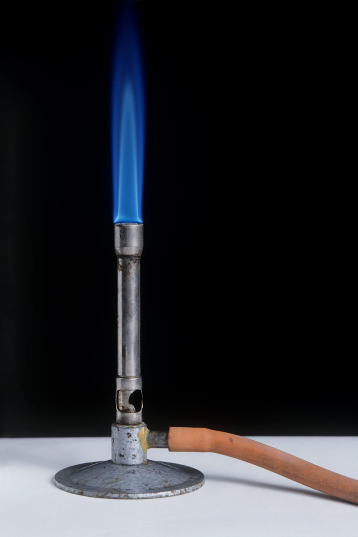 Na slici je prikazan Bunsenov plamenik. Uzak je i stoji uspravno na postolju. Na vrhu plamenika je plavičasti plamen.Građen je od metala.Crvena cijev dovodi plin do plamenika.