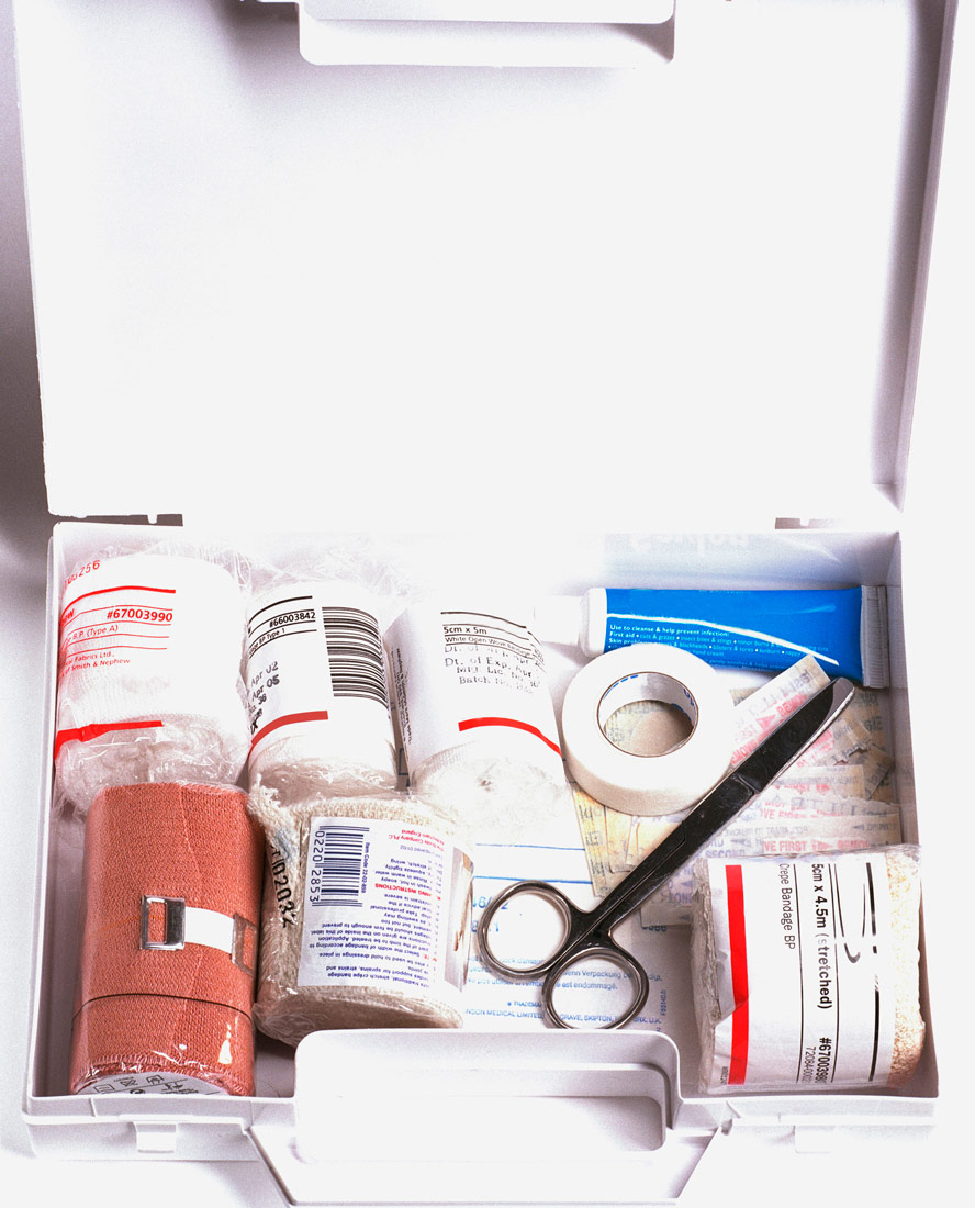 Na slici je prikazana kutija s priborom za prvu pomoć. Unutra su zavoji, škarice, medicinski flaster i drugo.