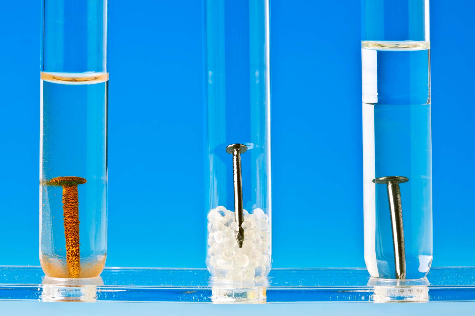 Fotografija prikazuje tri epruvete. U svakoj je željezni čavao. U prvoj epruveti čavao je u vodii zahrđao je, vidi se smeđa hrđa. U drugoj epruveti stavljen je u neku kristaliziranu čvrstu bijelu tvar. i na zraku je. Nema nikakvih promjena. U trećoj epruveti čavao je prikazan u uljnoj otopini i nema promjena.Možemo zaključiti da se u prvoj epruveti pojavila hrđa i čavao je promejnio boju u smeđu sa smeđim talogom na dnu epruvete. Znači da je došlo de kemijske promjene.