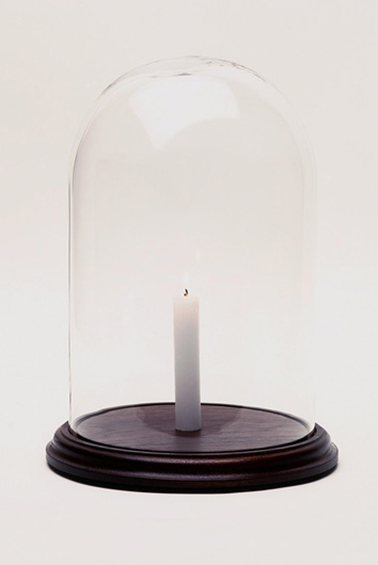 Na slici je prikazana bijela svijeća pod staklenim zvonom. Podložak zvona je crne boje.Nakon što se potroši kisik svijeća prestaje goriti