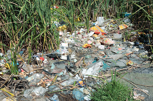 Fotografija prikazuje neodgovorno odlaganje otpada. Nerazgradiv plastični otpad odbačen je u prirodi.