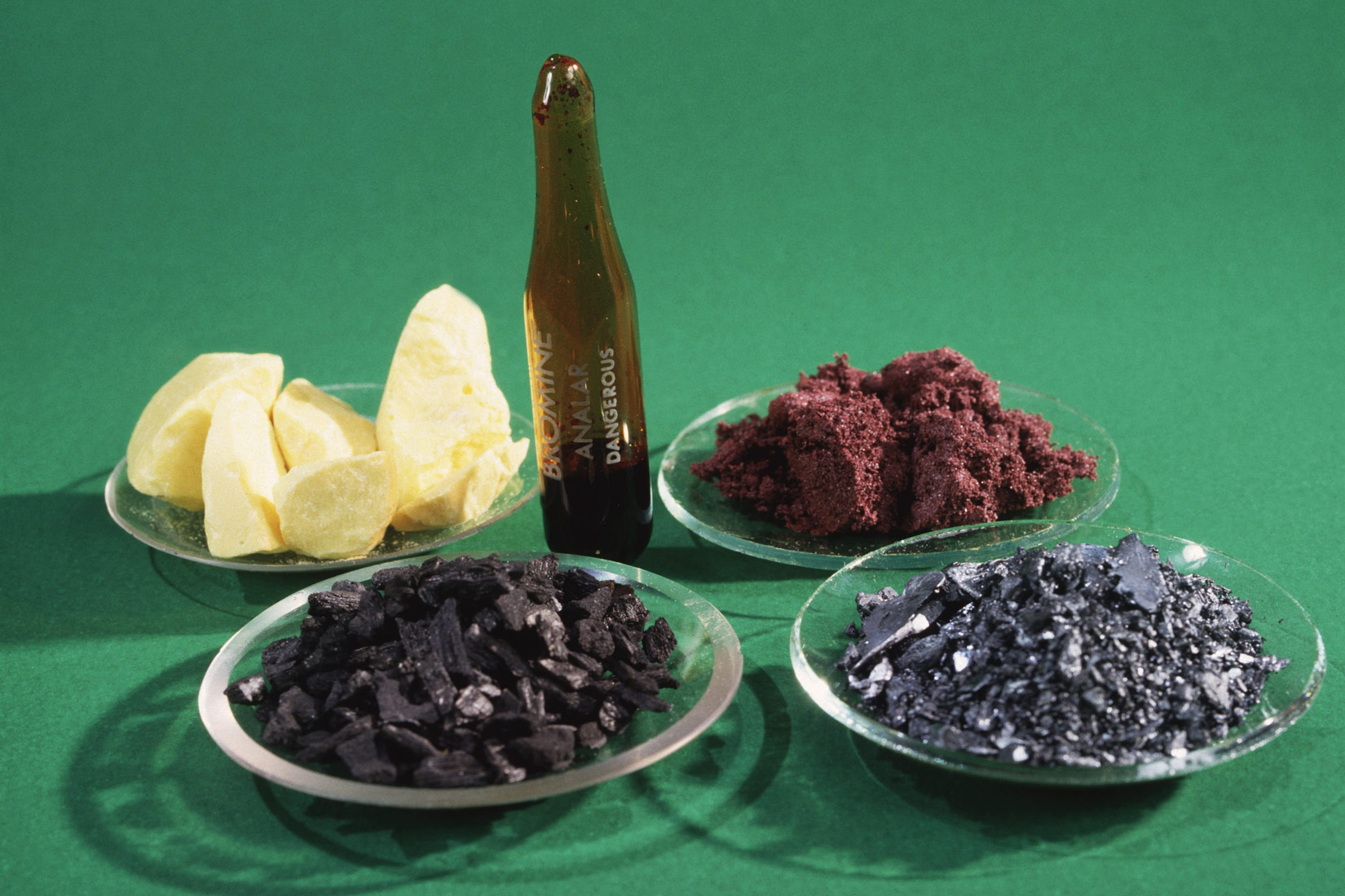 Fotogafija prikazuje uzorke nemetala. Sumpor: čvrsta tvar žute boje, različitih oblika, glatkih površina. Brom: u bočici, u tekućem stanju. Fosfor: crveni prah. Jod: crni komadići. Ugljik: sivi komadići, uzorak iz obične olovke.