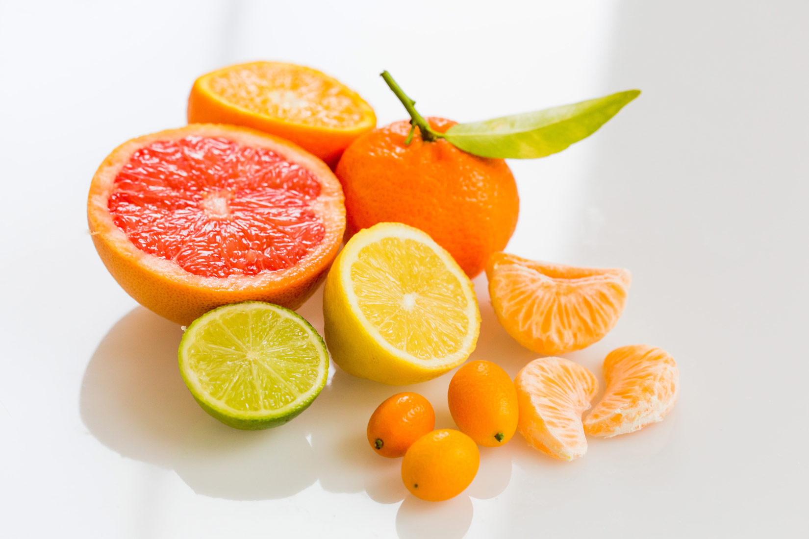 Fotografija prikazuje različito voće – naranče, limun, limetu, šipak i mandarinu.
