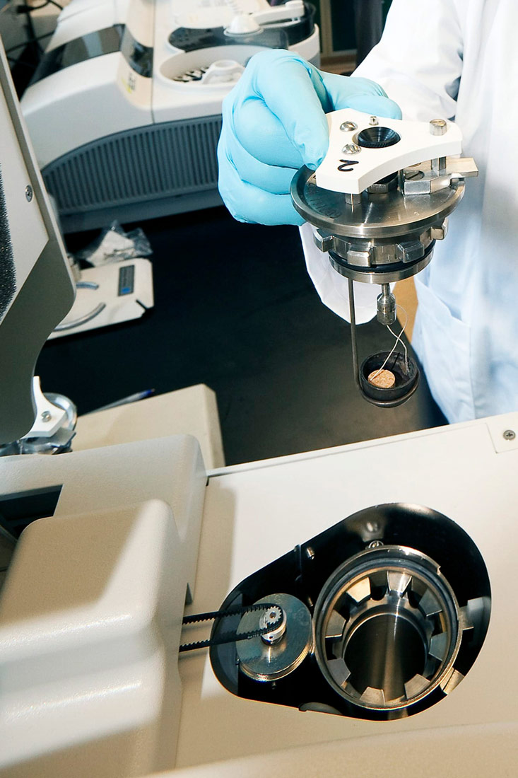 Fotografija prikazuje istraživača u laboratoriju. Ispred njega, na stolu, nalazi se aparat za određivanje vrijednosti hrane na osnovi njezina sagorijevanja.