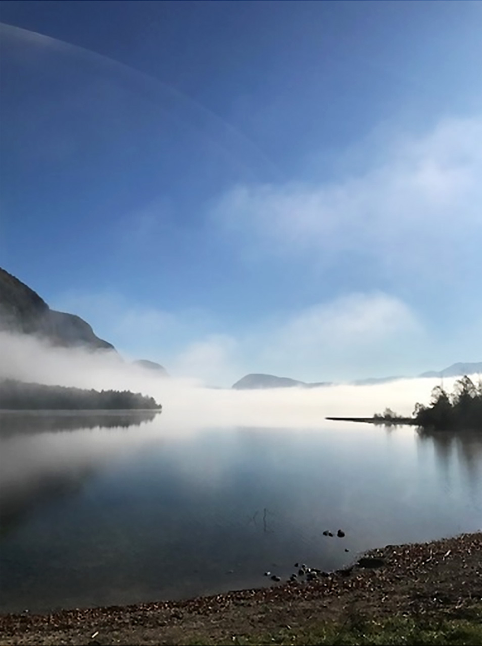 Izmaglica na jezeru okruženom planinama. 