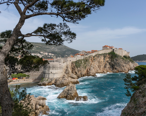 Snimka na kojoj vidimo dio zidina Dubrovnika koje su izgrađene na oštvroj stijeni i zapjenjeno more koje o stijenu udara