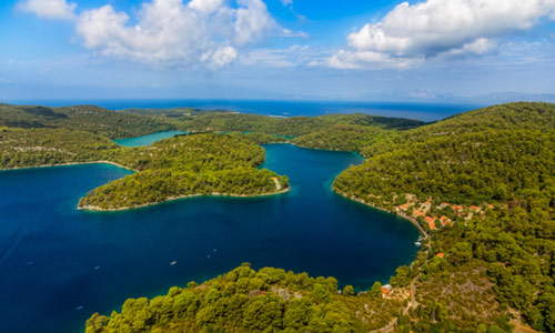 Jezero usred kojeg je otok. U daljini se vidi more, a otok je zelen