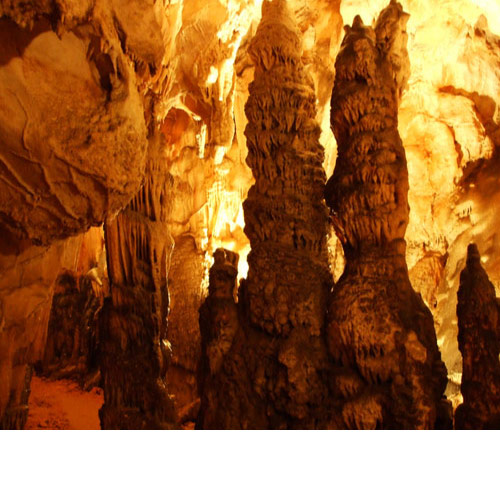 Jako osvjetljena unutrašnjost špilje sa stalagmitima. Svjetlost daje stjenama žuto narančastu boju