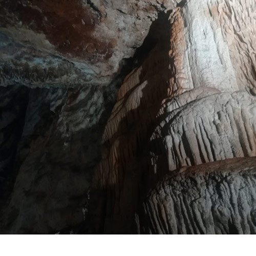 Unutrašnjost špilje sa stalaktitima. Stijene su bijele te svijetlo sive boje. Na fotografije se ističu stalagtiti koji nalikuju na stupiće koji se nalaze uz sam rub špilje