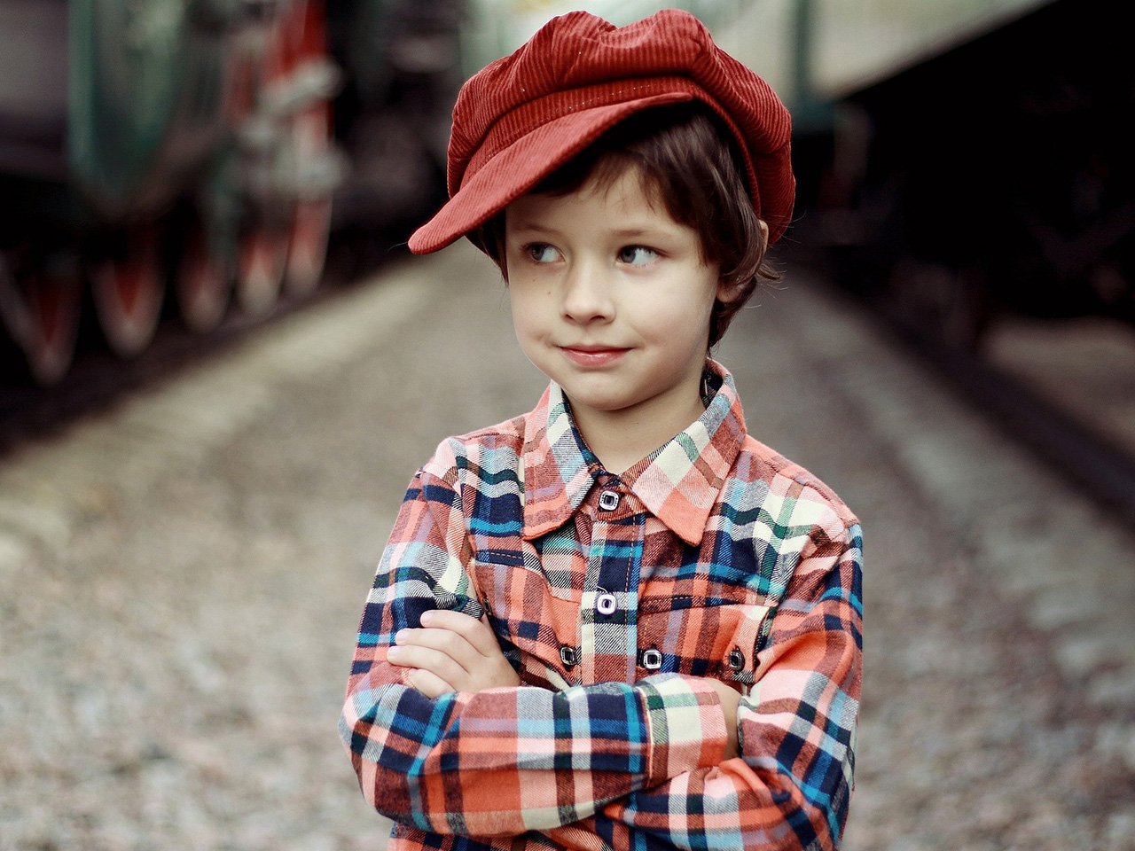 Dječačić u kariranoj košulji i s crvenom kapom na glavi.