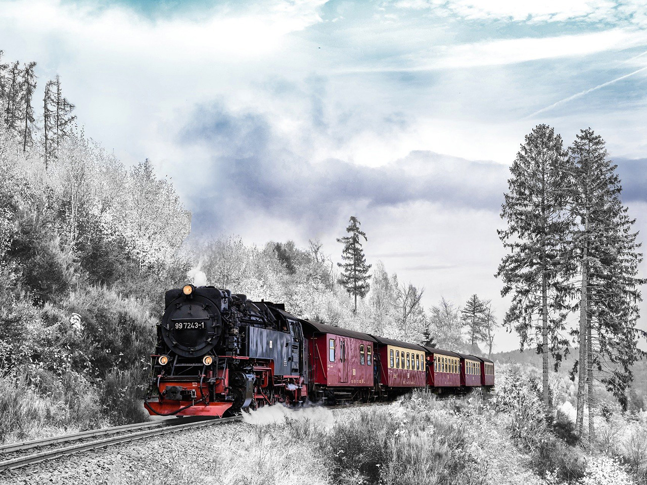 Lokomotiva na ugljen vuče pet vagona na svom putu kroz krajolik prekriven snijegom. 
