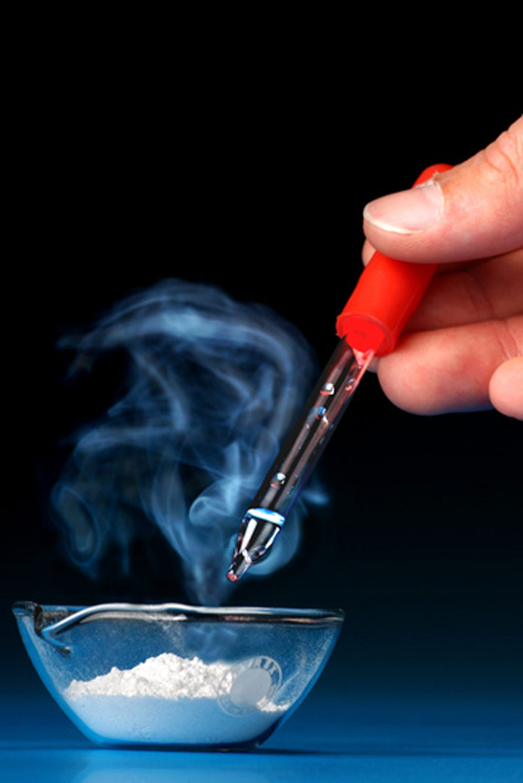 Gašenje vapna; Vapno je u praškasto i bijele boje.Smješteno je u staklenu, prozirnu zdjelicu.Iznad vapna netko kapaljkom kapa vodu.Kapaljka ima crvenu gumu.