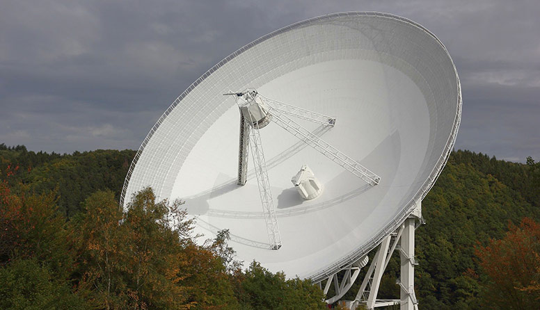 Prikazan je radioteleskop Effelsberg. Radioteleskop je bijelosive boje, okruglog oblika. Sastoji od kolektora koji ima ulogu objektiva teleskopa.  Kolektor prikuplja radio valove pristigle s nebeskih objekata.  U žarištu kolektora nalazi se antena.  U anteni radiovalovi izazivaju električne titraje.  Pomoću pojačala nastali električni napon mora se pojačavati i više milijuna puta.  